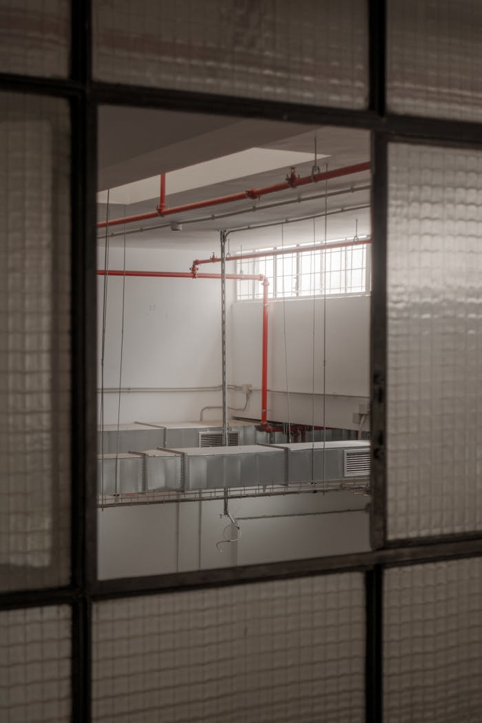 Interior view of an industrial warehouse with ventilation ducts and red pipes.